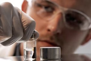 一位研究人员检查了磁铁矿颗粒，这些颗粒被磁铁吸引到小瓶的右侧。（弗赖贝格亥姆霍兹资源技术研究所）